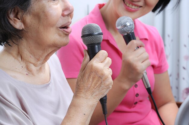 Oudere vrouw zingt thuis een lied met dochter.