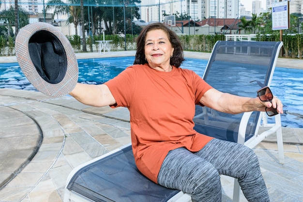 Oudere vrouw zit bij het zwembad