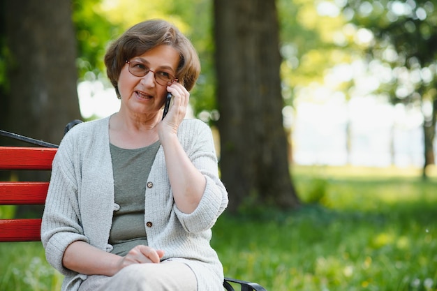 Oudere vrouw zit en ontspant op een bankje buiten in het park