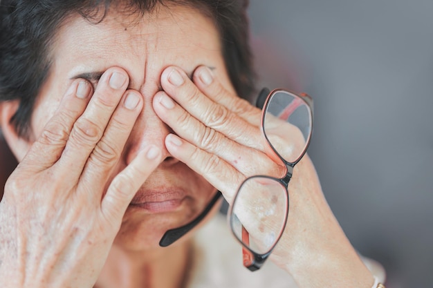 Oudere vrouwen wrijven in hun ogen of raken hun ogen aan vanwege vermoeidheid van de ogen door veel gebruik van hun ogen