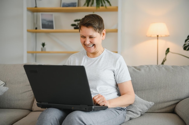 Oudere vrouwen zitten op de bank en houden op schoot laptop zoekinformatie controleren of typen van e-mail tijd doorbrengen online moderne technologie gemakkelijk interessant tijdverdrijf diensten voor gepensioneerd concept van de oudere generatie