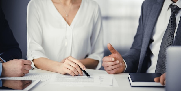 Oudere zakenman en groep zakenmensen die contract in functie bespreken. Vrouw en advocaten werken samen tijdens vergadering. Teamwerk en samenwerking.