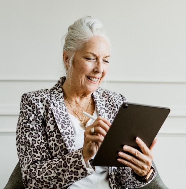 Oudere zakenvrouw die met een stylus notitie neemt op een digitale rablet