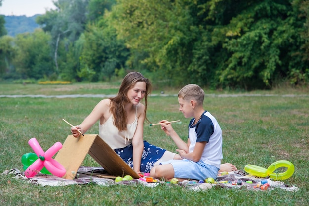 Oudere zus probeert haar broer te leren schilderen in het park