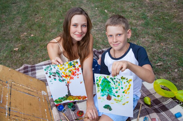 Oudere zus probeert haar broer te leren schilderen in het park