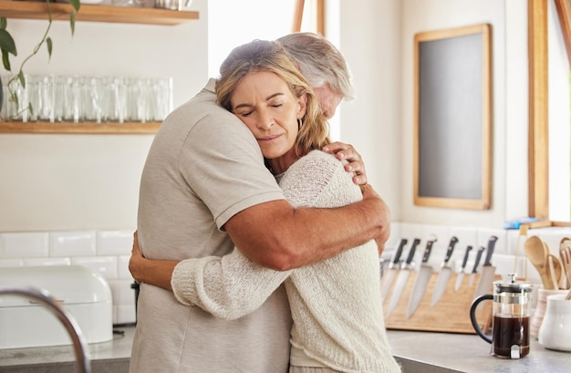 Ouderen paar en knuffel in keuken in huis samen romantiek en liefde Zorg man en vrouw met pensioen houden van huwelijk en omarmen op droevig moment voor ondersteuning, comfort en eenheid als getrouwde mensen