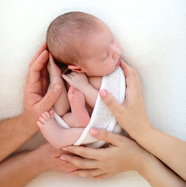 Ouders aanraken pasgeboren kind in deken