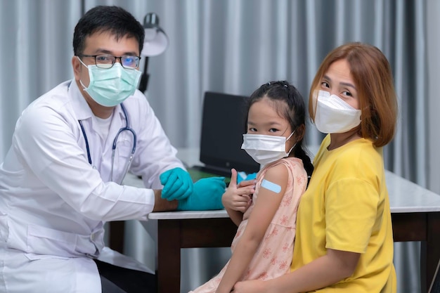 Ouders brengen hun dochter naar de dokter voor griepvaccinatie De moeder bracht het kind naar de dokter in de kliniek