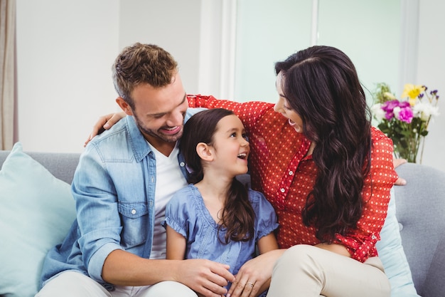 Ouders die terwijl het zitten met dochter op bank glimlachen