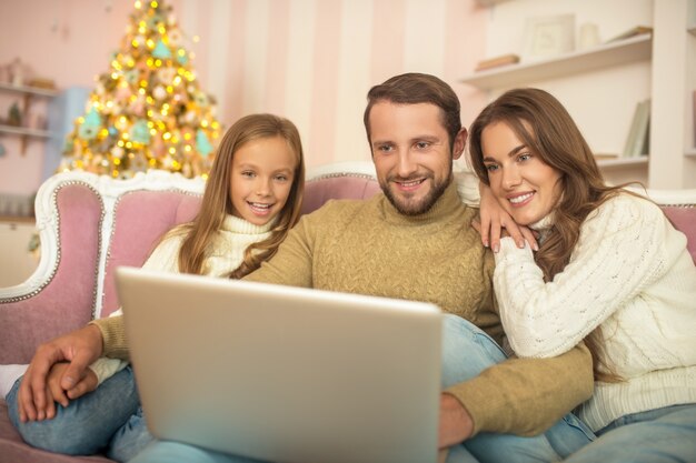 Ouders en hun dochter kijken naar iets op een laptop