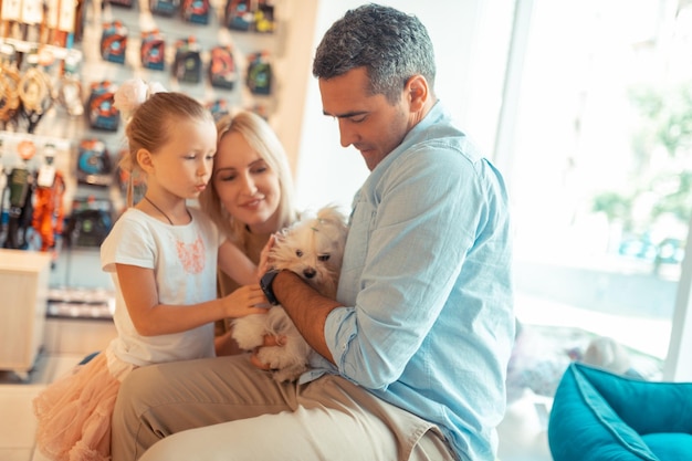 Ouders en hun schattige meisje nemen pluizige witte hond mee naar de dierenwinkel