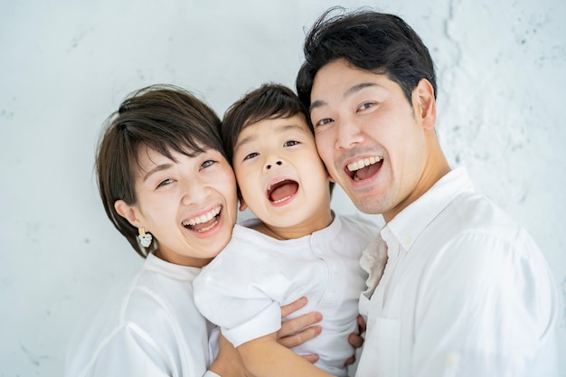 Ouders en kind opgesteld met een glimlach en een gestructureerde witte achtergrond