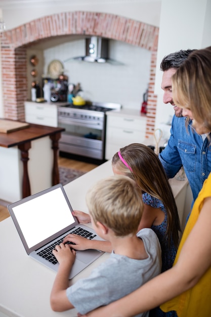 Ouders en kinderen met behulp van laptop in de keuken