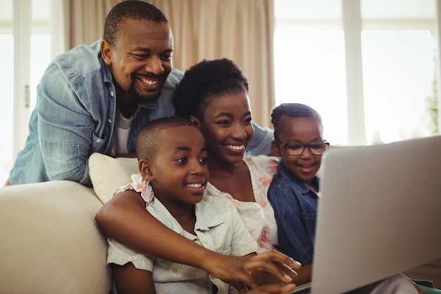 Ouders en kinderen met behulp van laptop in de woonkamer