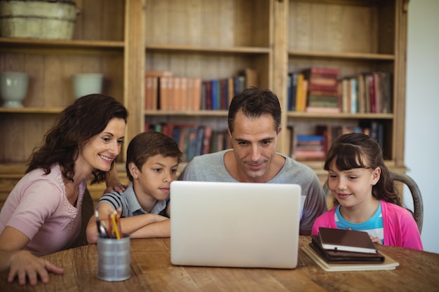 Ouders en kinderen met behulp van laptop op tafel in de studeerkamer