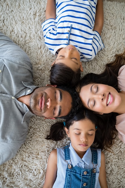 Ouders en kinderen ontspannen op tapijt in de woonkamer