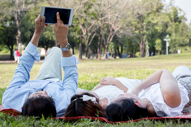 Ouders en kinderen spelen de tablet op de mat in het park.