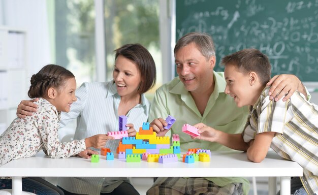 Ouders en kinderen spelen met kleurrijke plastic blokken in de klas