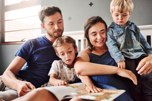 Foto ouders en kinderen zitten thuis op het bed.