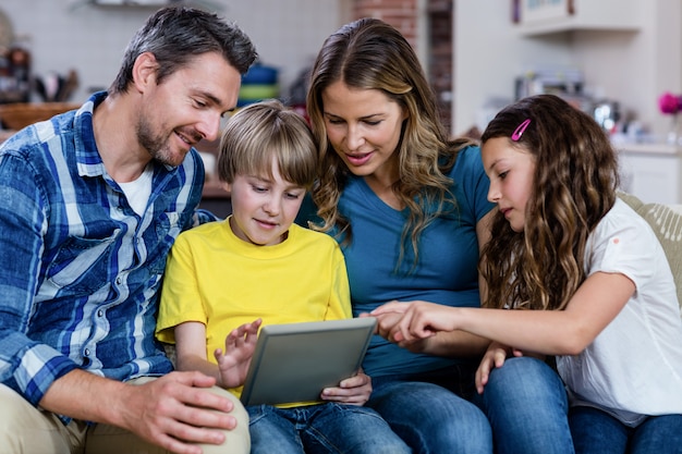 Ouders en kinderen zittend op een bank en met behulp van een digitale tablet