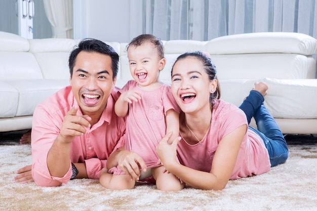 Ouders en schattige dochter lachen in de woonkamer