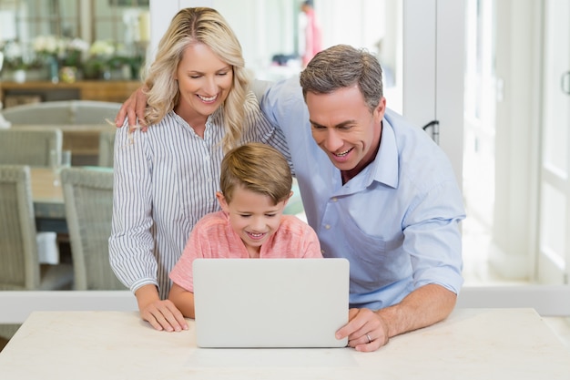 Ouders en zoon die laptop thuis met behulp van