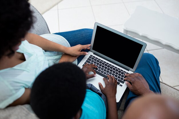 Ouders en zoon met behulp van laptop in de woonkamer