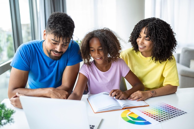 Ouders helpen kind thuis met haar huiswerk Vader en moeder helpen dochter thuis studeren Kleine meisjes voltooien hun oefeningen met de hulp van thuisonderwijsconcept van vader en moeder