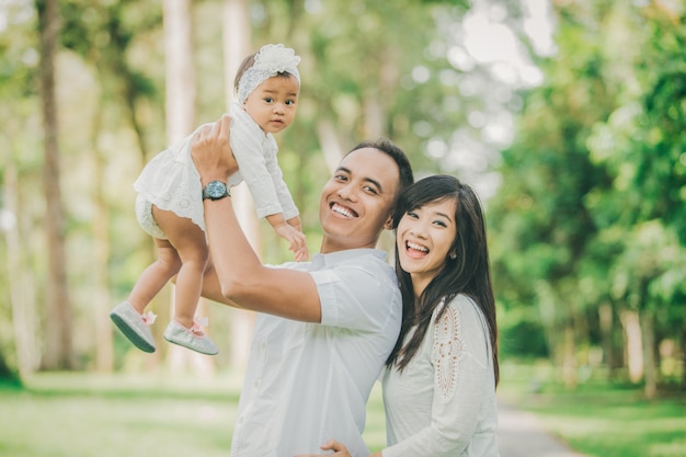 Ouders in witte kleren lopen met hun dochtertje in het park