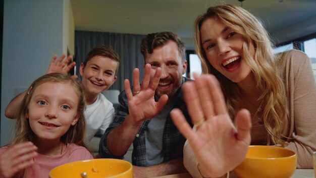 Ouders kinderen kijken camera naar huis Familie zwaaien met handen tijdens ochtendvideogesprek