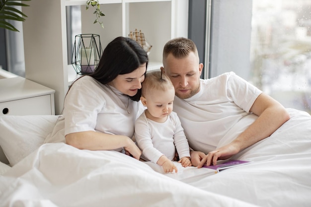 Ouders lezen babyboek met dochter thuis in bed