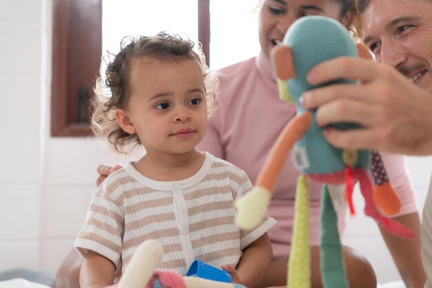 Foto ouders met een klein meisje spelen samen met uw nieuwe speelgoed in de slaapkamer speelgoed dat het denkvermogen van kinderen verbetert