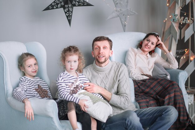 Ouders met hun dochtertjes zitten kerstavond in de huiskamer.