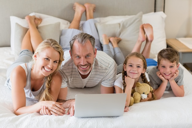 Ouders met hun kinderen liggend op bed en het gebruik van laptop in de slaapkamer