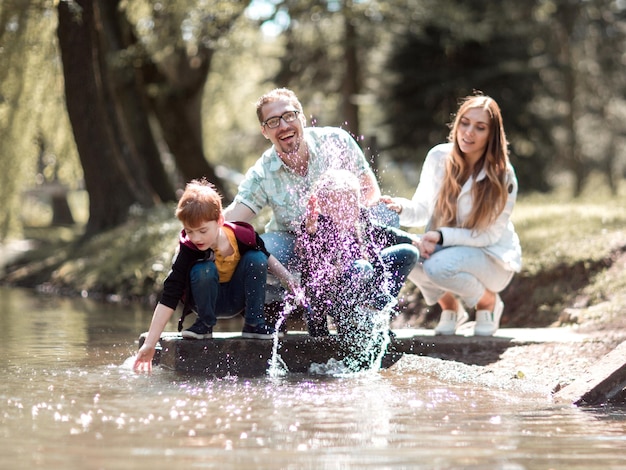 Ouders met kinderen ontspannen in de buurt van het meer in het park het concept van familie-entertainment