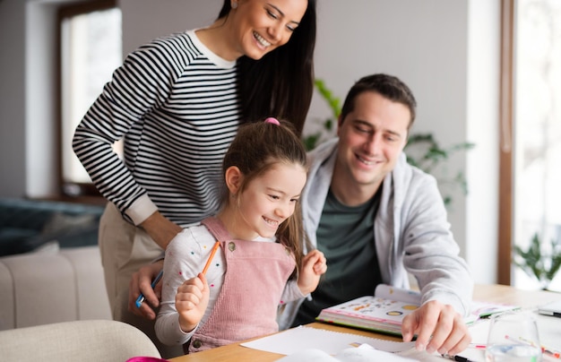 Ouders met schoolmeisje binnenshuis, afstandsonderwijs en thuiskantoorconcept.