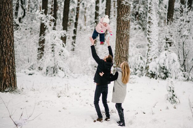 Ouders spelen met haar dochter in winter forest park.