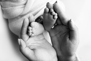 Ouders39 handpalmen vader en moeder houden de benen van een pasgeboren baby voeten van een pasgeborene in de handen van ouders foto van de voet, hielen en tenen zwart-wit studio macro-opname