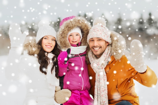 ouderschap, mode, gebaar, seizoen en mensenconcept - gelukkig gezin met kind in winterkleren zwaaiende handen buitenshuis