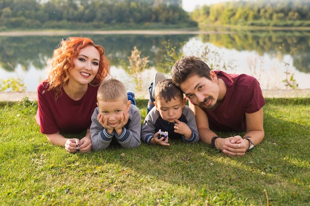 Ouderschap, natuur, mensenconcept - familie met twee zonen die dichtbij het meer zitten.