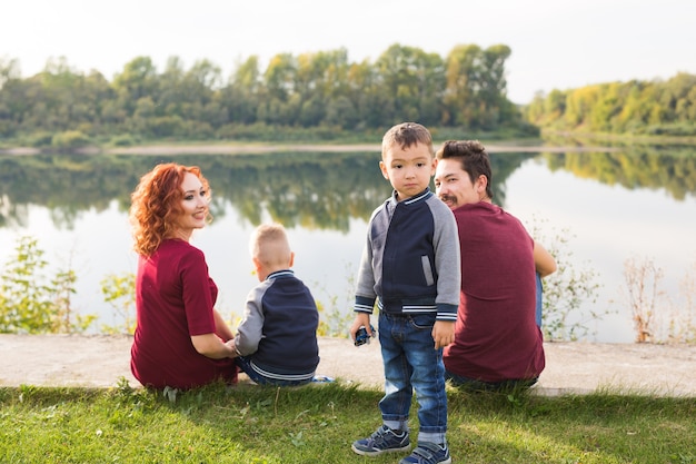 Ouderschap, natuur, mensenconcept - gezin met twee zonen die dichtbij het meer zitten.