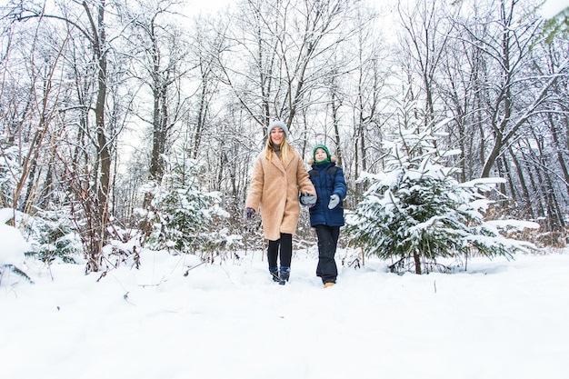 Ouderschap, plezier en seizoensconcept - Gelukkige moeder en zoon die plezier hebben en spelen met sneeuw in het winterbos.