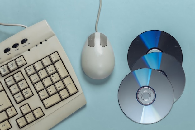 Ouderwetse retro toetsenbord-cd's en pc-muis op blauwe pastel
