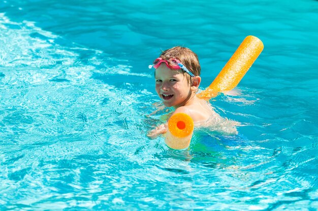 Foto attività estive all'aperto concetto di divertimento salute e vacanza felice ragazzo sorridente di cinque anni in occhiali da nuoto nuotare in piscina con noodle in una calda giornata estiva