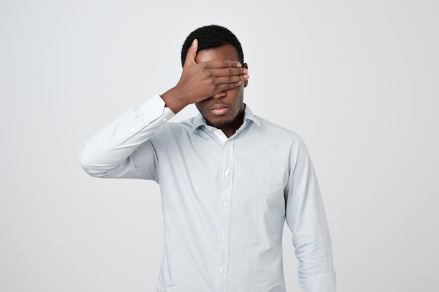 Oung uomo africano in camicia bianca che copre gli occhi