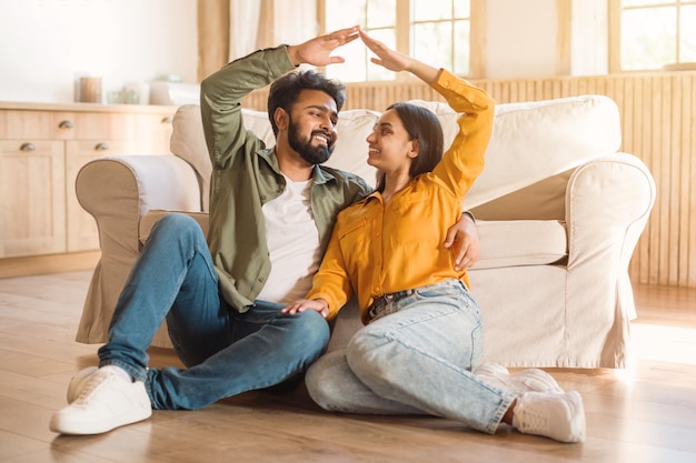 Oung couple making home shape with hands laughing