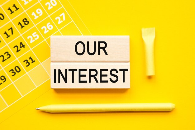 Our interest inscription on cubes , abstract calendar, yellow pen on a yellow background. a bright solution for business, financial, marketing concept