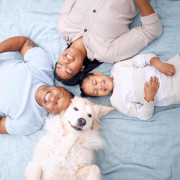 Our little family. Shot of a young family lying on the grass with their dog in their garden at home.