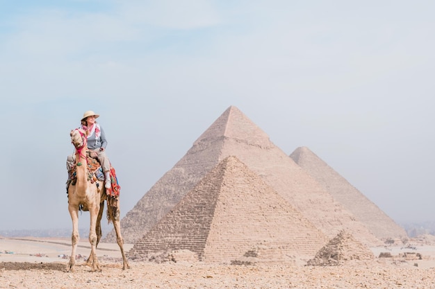 Ourist vrouw rijdt op een dromedaris voor piramides Egypte Cairo Giza