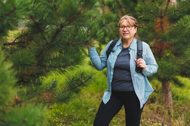 Outddor portret van gelukkige Europese vrouwelijke gepensioneerde met rugzak genieten van prachtige natuur tijdens nordic walking Ouder wordende mensen actieve levensstijl en gezondheidsconcept